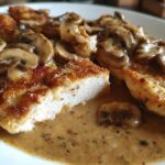 Close-up of pan-seared chicken marsala cut open, smothered in creamy mushroom sauce.