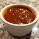 A close-up of thick, glossy Copycat Chick-fil-A Honey Roasted BBQ Sauce served in a small white ramekin.
