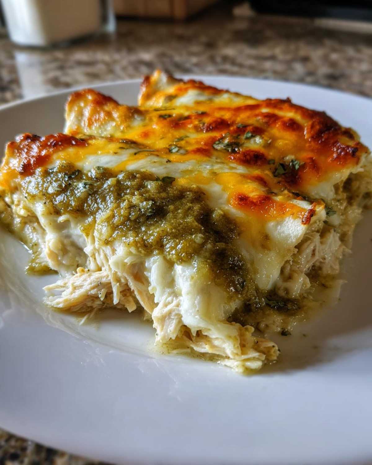 Close-up of two Creamy White Chicken Enchiladas with green chile sauce and melted, browned cheese.