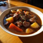 A close-up bowl of Easy Guinness Beef Stew with tender beef chunks, potatoes, and a large carrot piece.