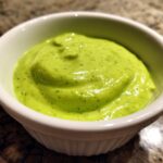 Close-up of creamy, bright green Five-Minute Avocado Lime Dressing in a small white ramekin.