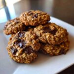 A stack of freshly baked Gluten-Free Irish Oat Cookies with visible dark chocolate chunks on a white plate.