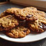 A stack of freshly baked Gluten-Free Irish Oat Cookies with melted dark chocolate chunks on a white plate.