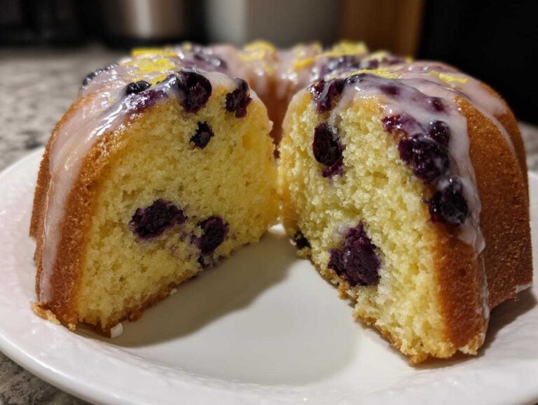 Close-up of a moist slice of Gluten-Free Lemon Blueberry Bundt Cake with lemon glaze and visible blueberries.