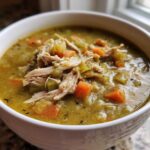Close-up of a hearty bowl of Instant Pot Split Pea Soup with Smoked Turkey, topped with shredded turkey and visible carrots.