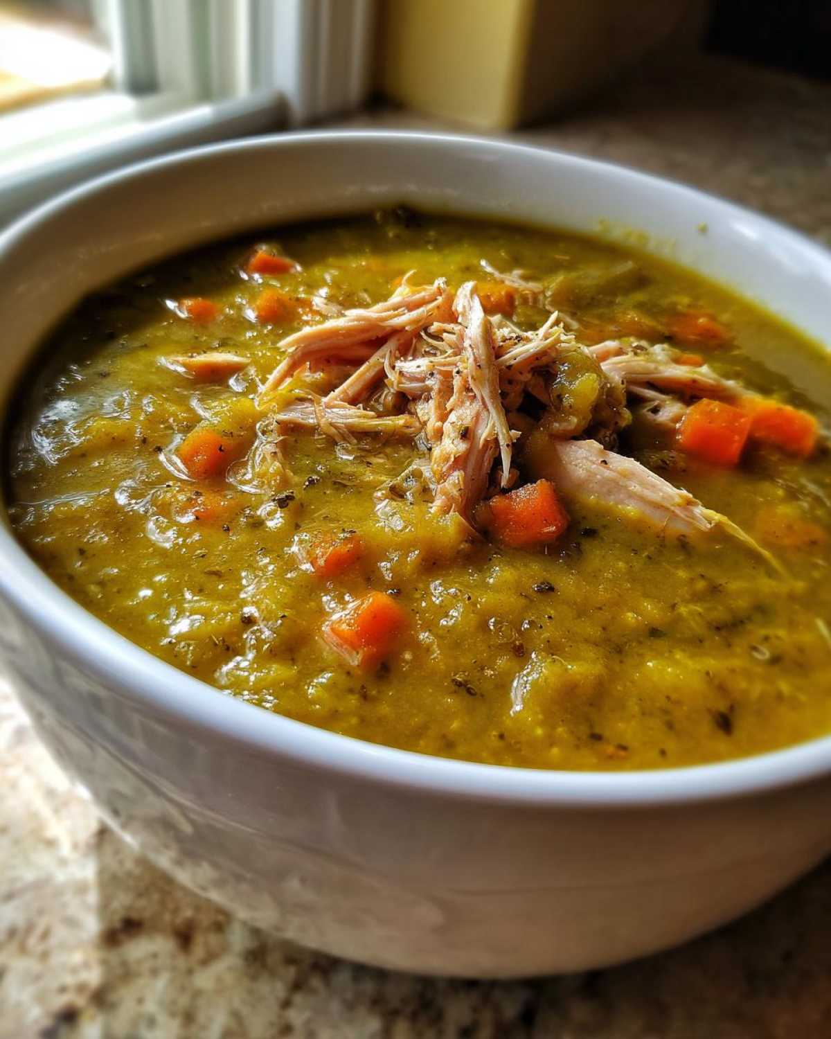 Close-up of thick Instant Pot Split Pea Soup with carrots and topped with shredded smoked turkey.