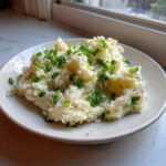 A white bowl filled with creamy Irish Champ Mashed Potatoes with Scallions, topped generously with fresh green onions.