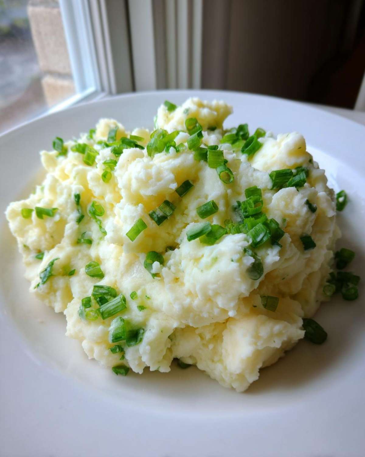 A mound of creamy Irish Champ Mashed Potatoes with Scallions generously topped with fresh green chives.