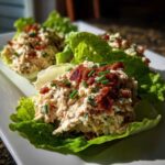 Three servings of Keto Bacon Ranch Chicken Salad Lettuce Boats topped with crumbled bacon and chives.
