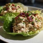 Two servings of Keto Bacon Ranch Chicken Salad Lettuce Boats topped with crumbled bacon and chives.