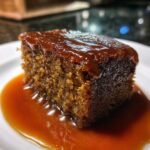 Close-up of a rich, moist square of sticky toffee pudding recipe drenched in toffee sauce.