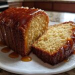 A slice cut from a loaf of moist sweet potato pound cake, generously topped with dripping caramel sauce.