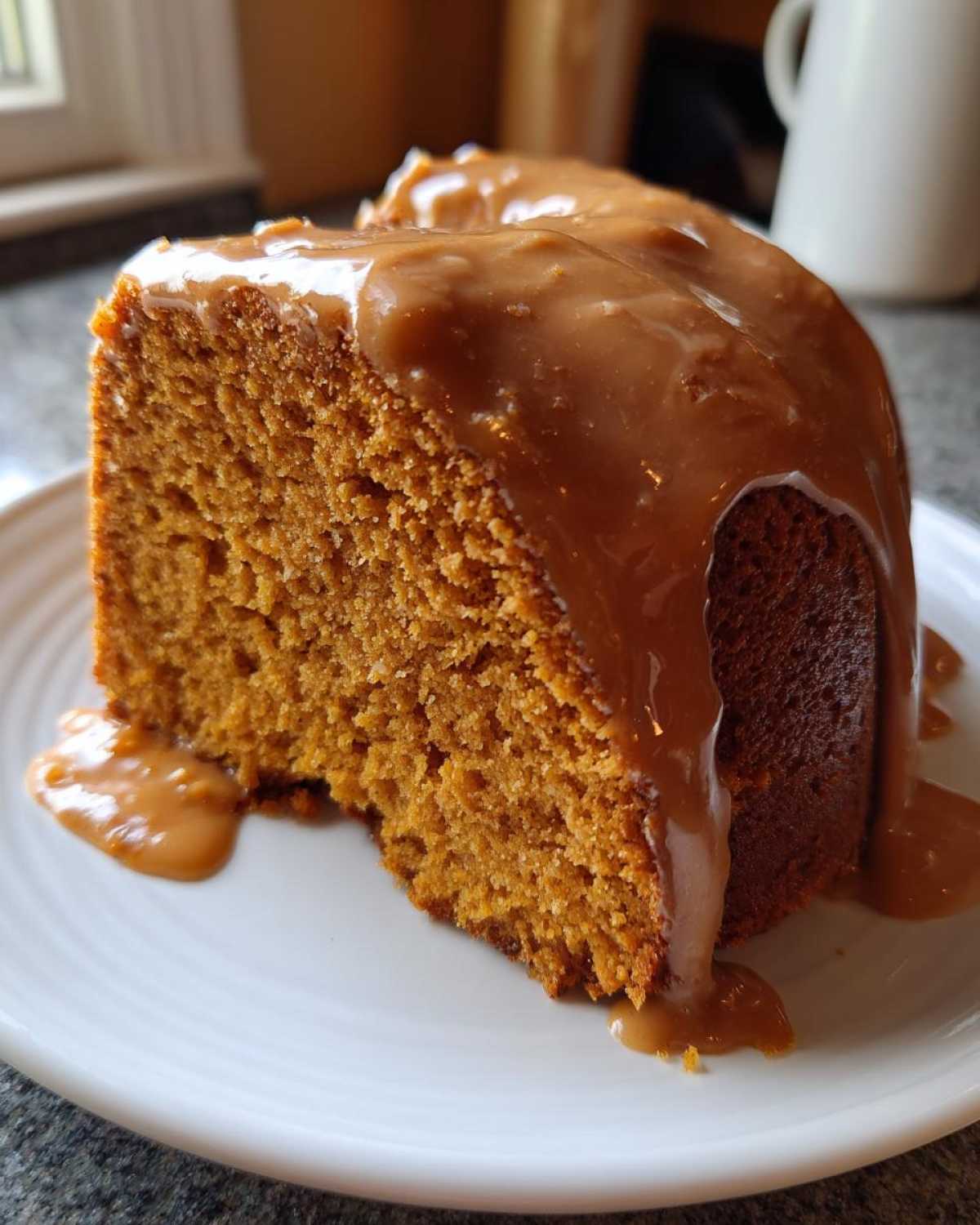 Close-up of a moist slice of sweet potato pound cake generously topped with a thick caramel-colored glaze.