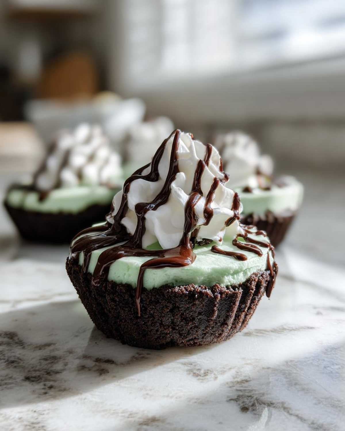 A close-up of one No-Bake Mint Chocolate Cheesecake Cup with a dark chocolate crust, mint filling, whipped cream, and chocolate drizzle.