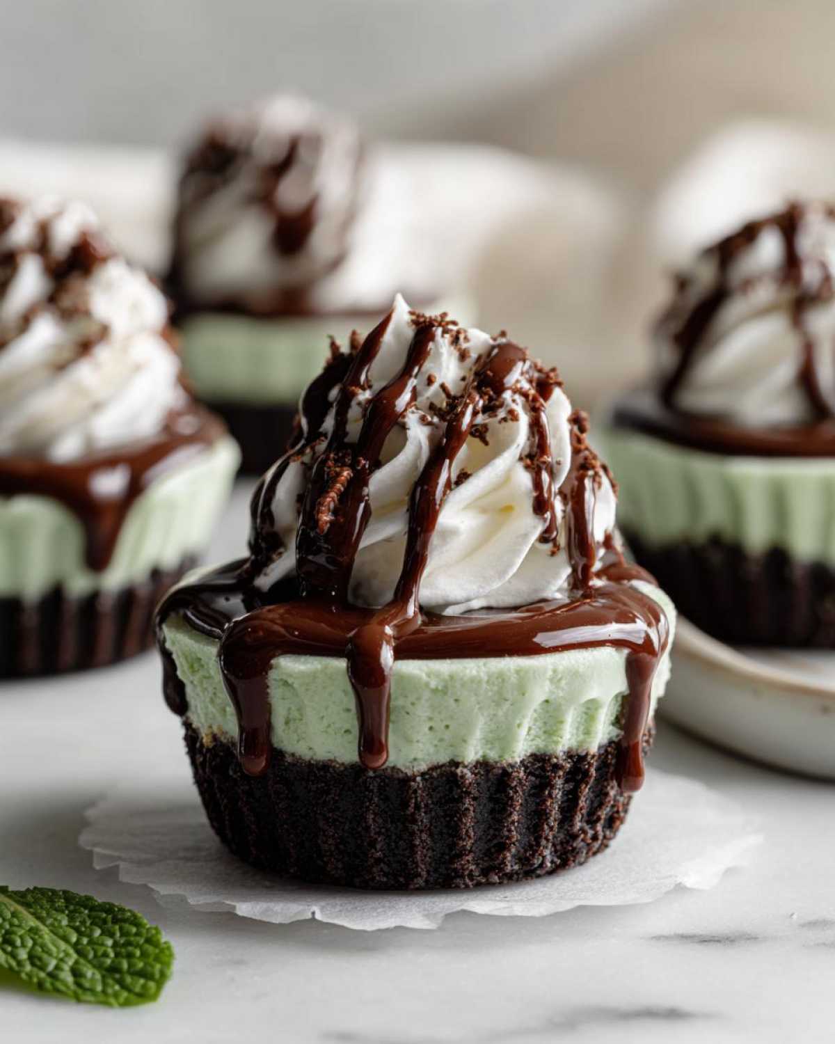 A single No-Bake Mint Chocolate Cheesecake Cup topped with whipped cream, chocolate drizzle, and sprinkles.