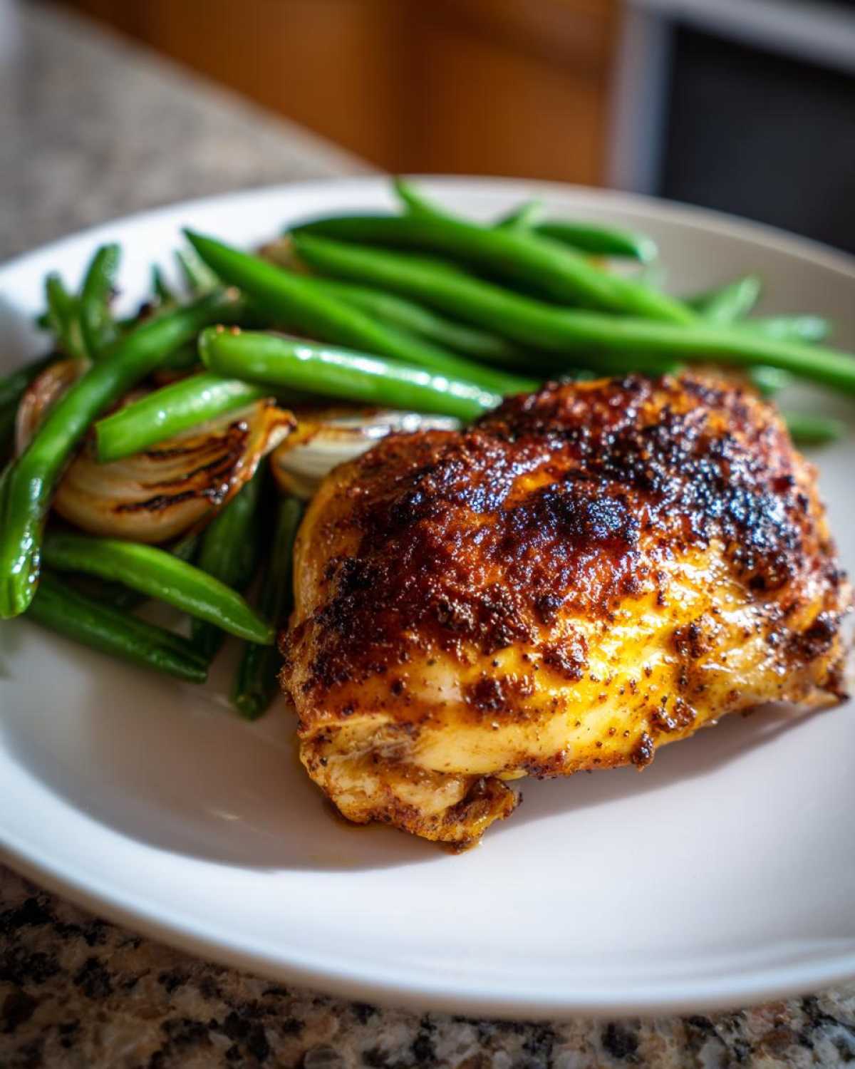 A close-up of a perfectly cooked piece of One-Pan Dijon Chicken with crispy skin, served alongside bright green beans and caramelized shallots.