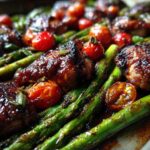 Close-up of Sheet Pan Honey Balsamic Chicken with Asparagus and roasted cherry tomatoes.