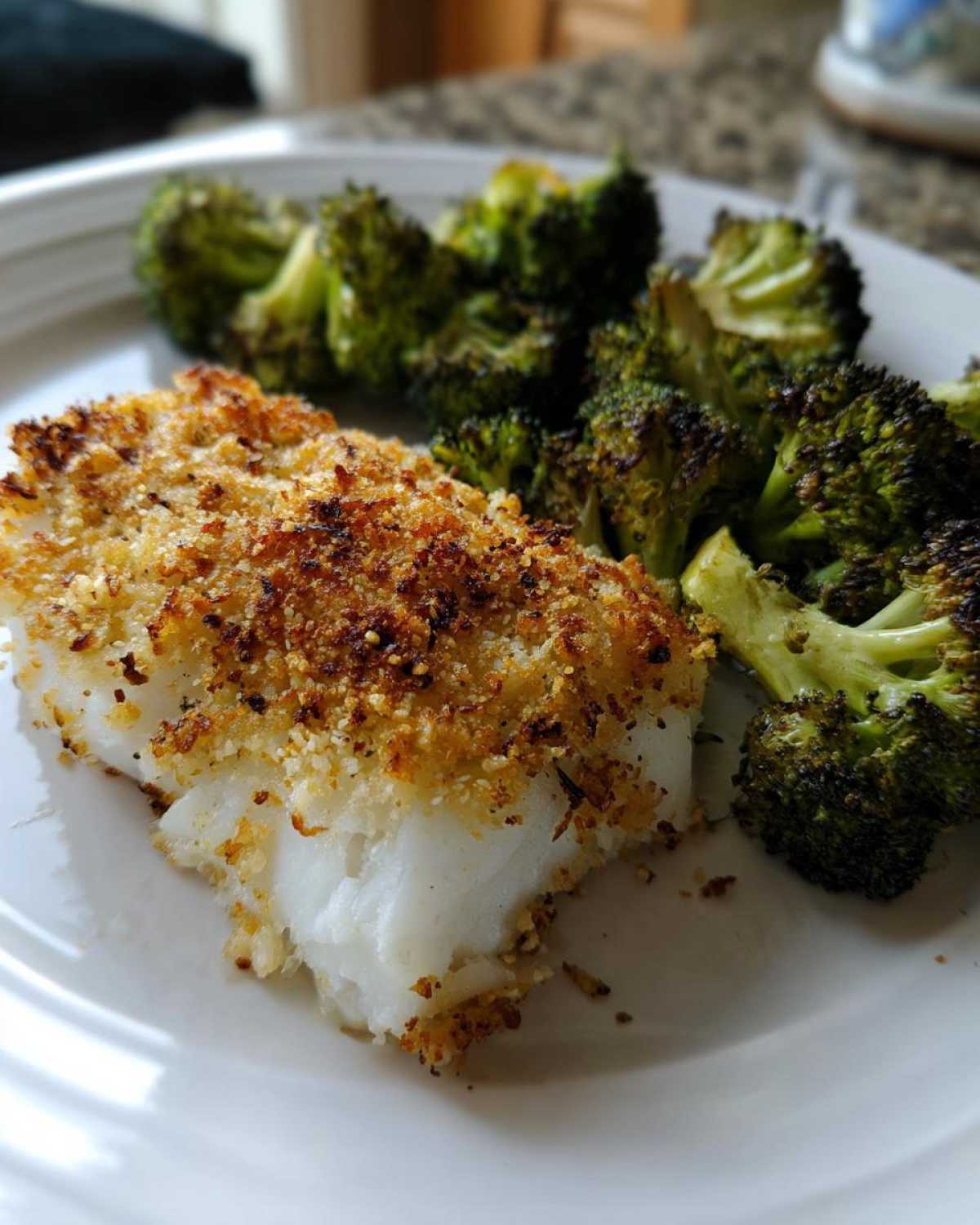 A serving of Sheet Pan Parmesan Crusted Cod with crispy, roasted broccoli florets on a white plate.