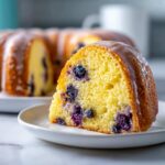 Close-up of a moist slice of Gluten-Free Lemon Blueberry Bundt Cake topped with a white glaze.