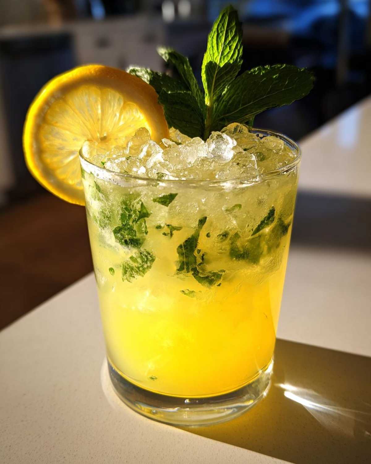 Close-up of a Sparkling Lemon Mint Mocktail filled with crushed ice, mint leaves, and garnished with a lemon slice.