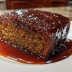 A close-up of a square slice of moist sticky toffee pudding recipe smothered in rich toffee sauce.