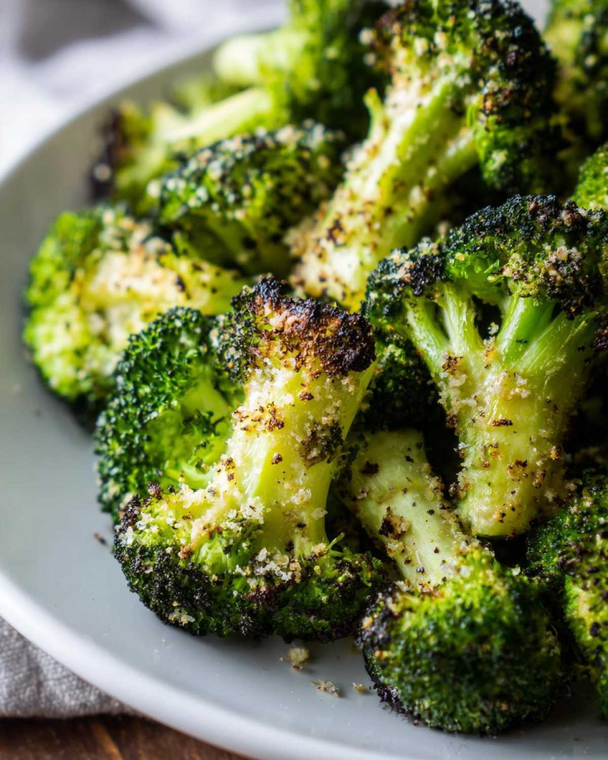 Close-up of perfectly cooked roasted broccoli florets seasoned with spices and a light dusting of cheese.