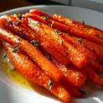 Close-up of beautifully glazed roasted carrots seasoned with herbs, ready to serve.