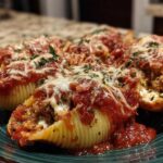 A close-up view of baked stuffed shells covered in rich tomato sauce, melted mozzarella, and parsley.