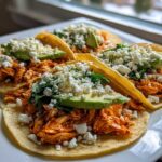 Four authentic Chicken Tinga Tacos loaded with shredded chicken, avocado slices, crumbled white cheese, and cilantro.