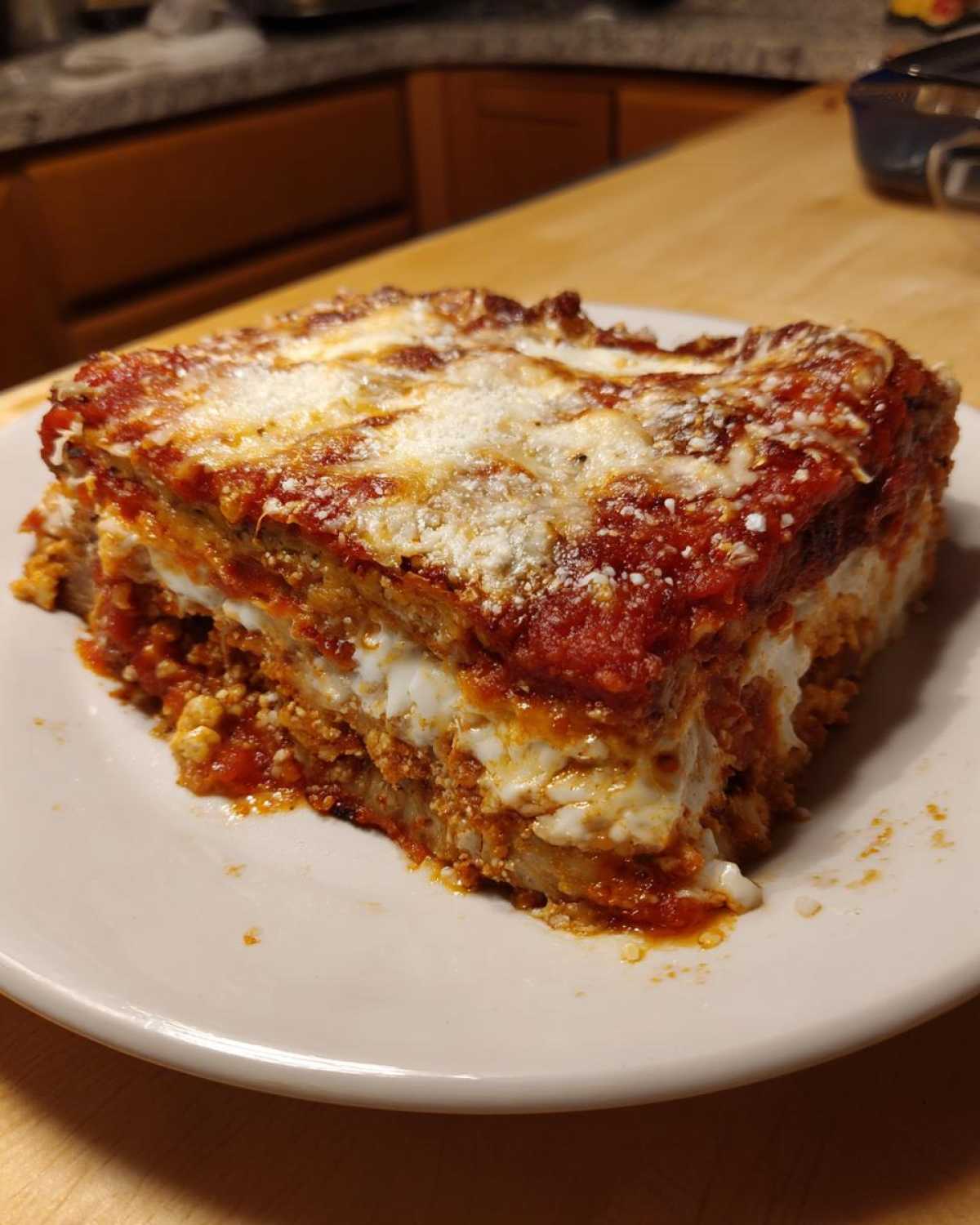 A thick, layered slice of Authentic Eggplant Parmesan Recipe covered in marinara sauce and melted cheese.