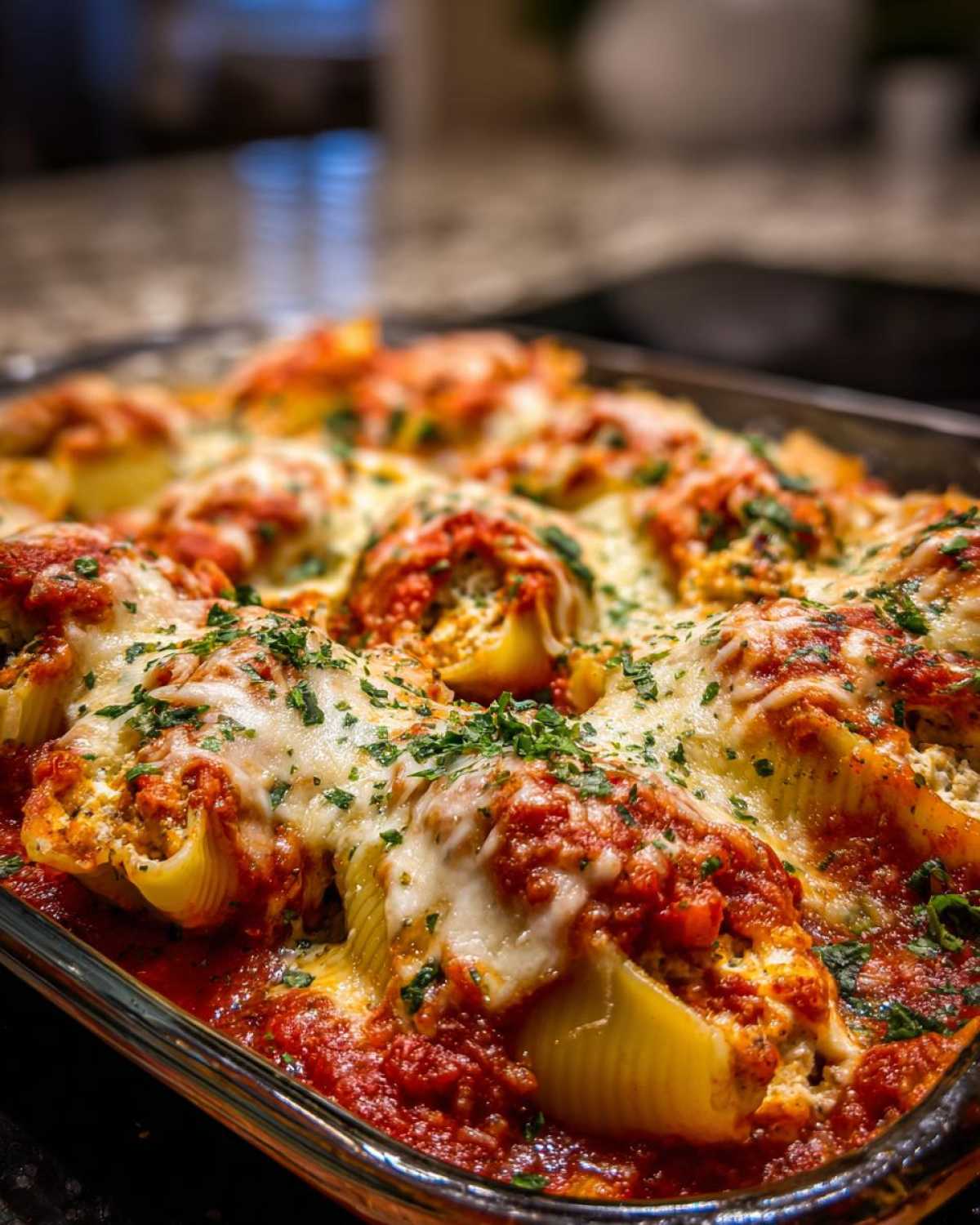 Close-up of baked stuffed shells covered in marinara sauce, melted mozzarella cheese, and fresh parsley.