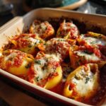 Close-up of baked stuffed shells covered in marinara sauce and melted mozzarella cheese, garnished with parsley.