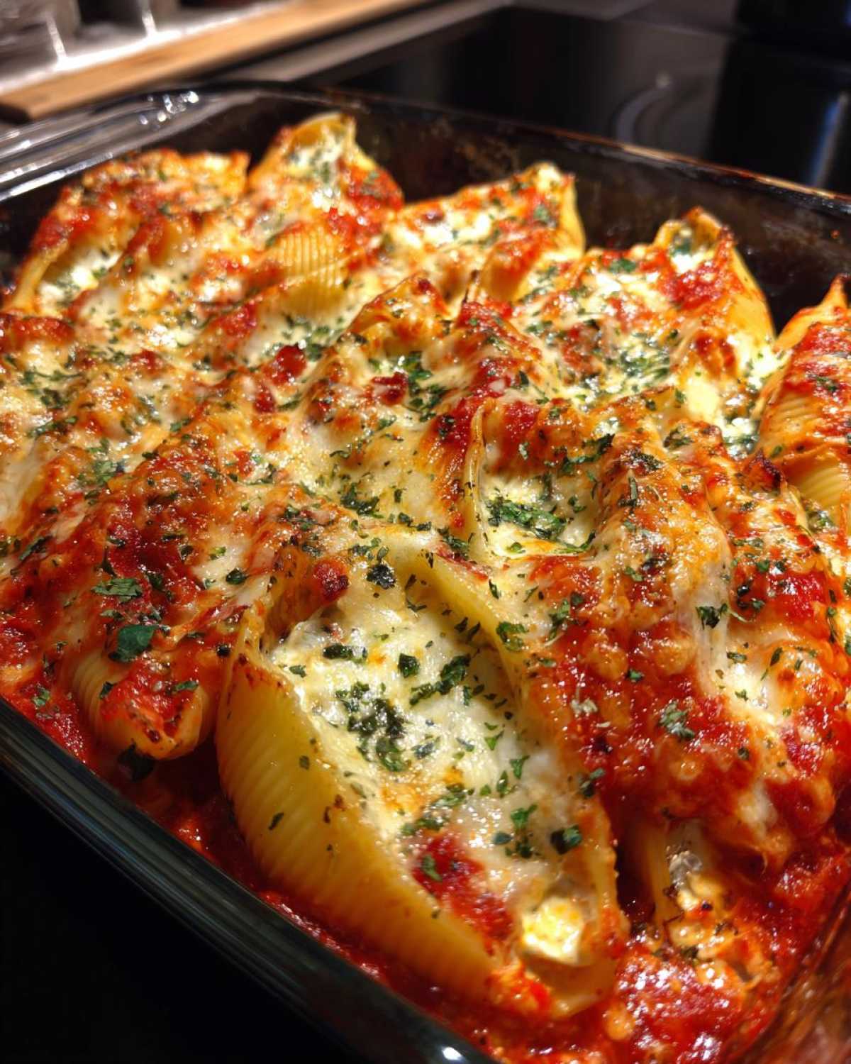 Close-up of baked stuffed shells covered in marinara sauce, melted mozzarella, and parsley.