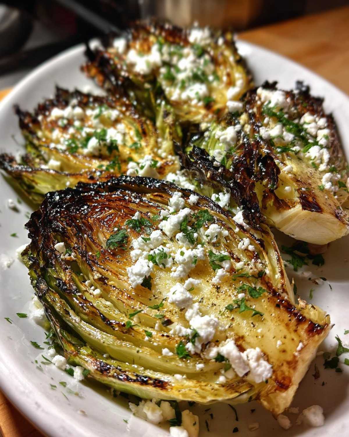 Four charred and tender Blistered Cabbage Steaks topped generously with crumbled feta cheese and fresh parsley.