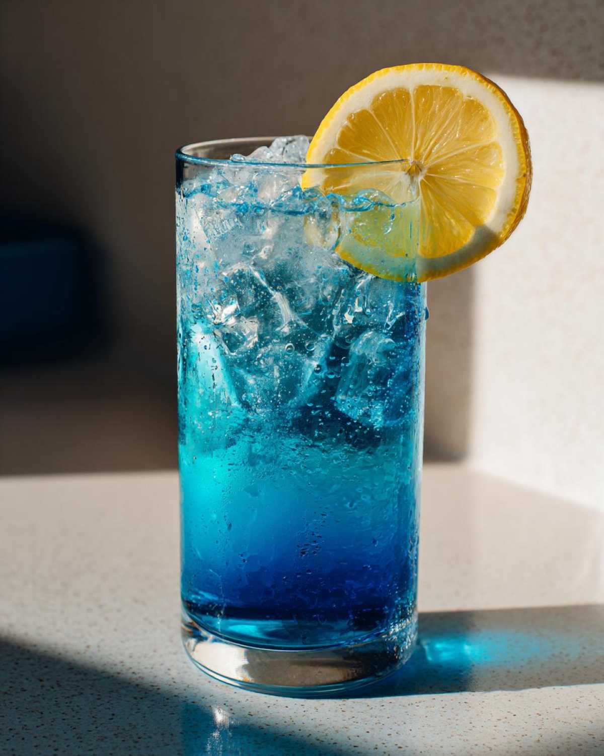 A tall glass filled with an icy, vibrant Blue Drinks Aesthetic Cocktail garnished with a bright lemon slice.