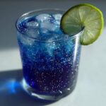 A stunning Blue Drinks Aesthetic Mocktail featuring deep blue liquid, edible glitter, ice, and a fresh lime wheel garnish.