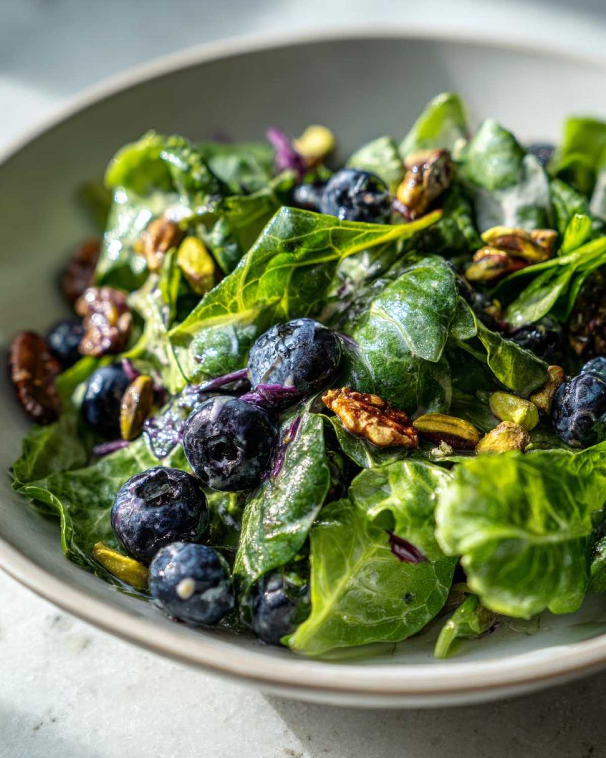 Close-up of vibrant greens, fresh blueberries, and pistachios tossed in a light dressing for the Blueberry Pistachio Spring Salad.