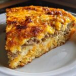 Close-up of a hearty slice of breakfast casserole with cream of mushroom, showing layers of sausage and melted cheese.
