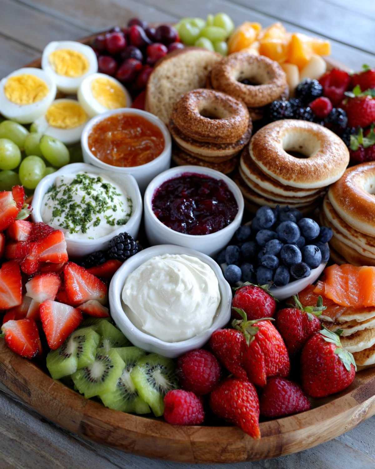 A vibrant Breakfast Grazing Board for Moms featuring bagels, fruit, cream cheese, and hard-boiled eggs.