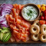 Overhead view of a beautiful Breakfast Grazing Board with Smoked Salmon, sliced red onions, avocado, cream cheese dip, and mini bagels.