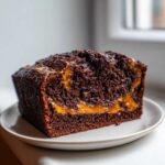 A close-up of a rich, dark chocolate Brownie Bread slice featuring a gooey caramel swirl filling.