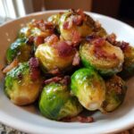 Close-up of vibrant Brussels sprouts with maple bacon glaze and crispy bacon bits served in a white bowl.
