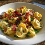 Close-up of creamy Burrata Pea and Prosciutto Tortellini topped with crispy prosciutto pieces and fresh parsley.