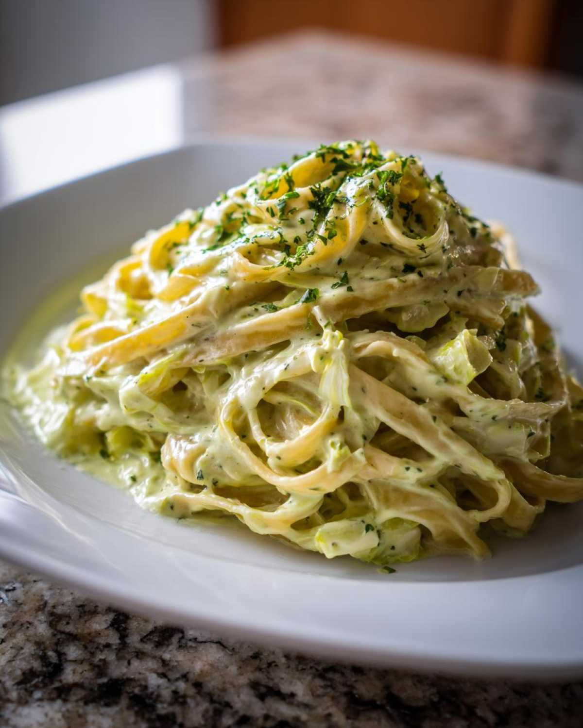 A close-up of fettuccine pasta tossed in a creamy Cabbage Alfredo Pasta Sauce, garnished with parsley.
