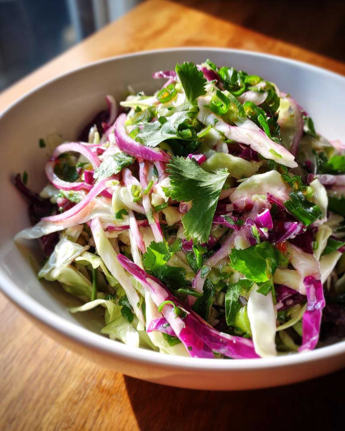 Close-up of a fresh Cabbage and Lime Zesty Salad featuring shredded green and red cabbage, red onion, and cilantro.