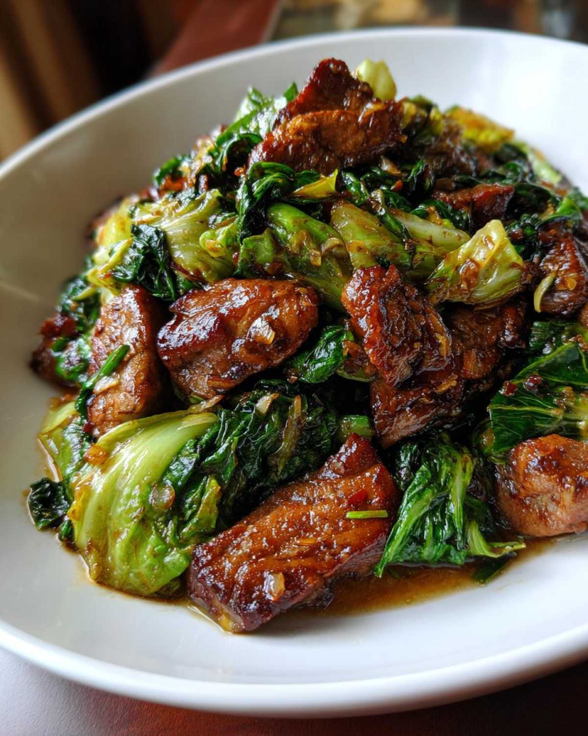 Close-up of glossy, caramelized pork pieces mixed with wilted cabbage in a rich sauce for Cabbage and Pork Stir Fry Ginger.