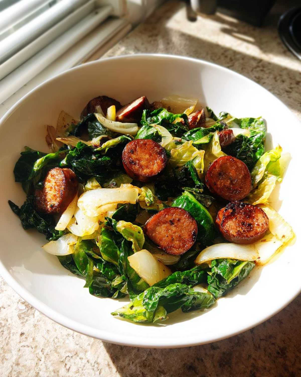 A white bowl filled with a quick Cabbage and Sausage Skillet 15 Minutes, featuring browned sausage slices and wilted greens.