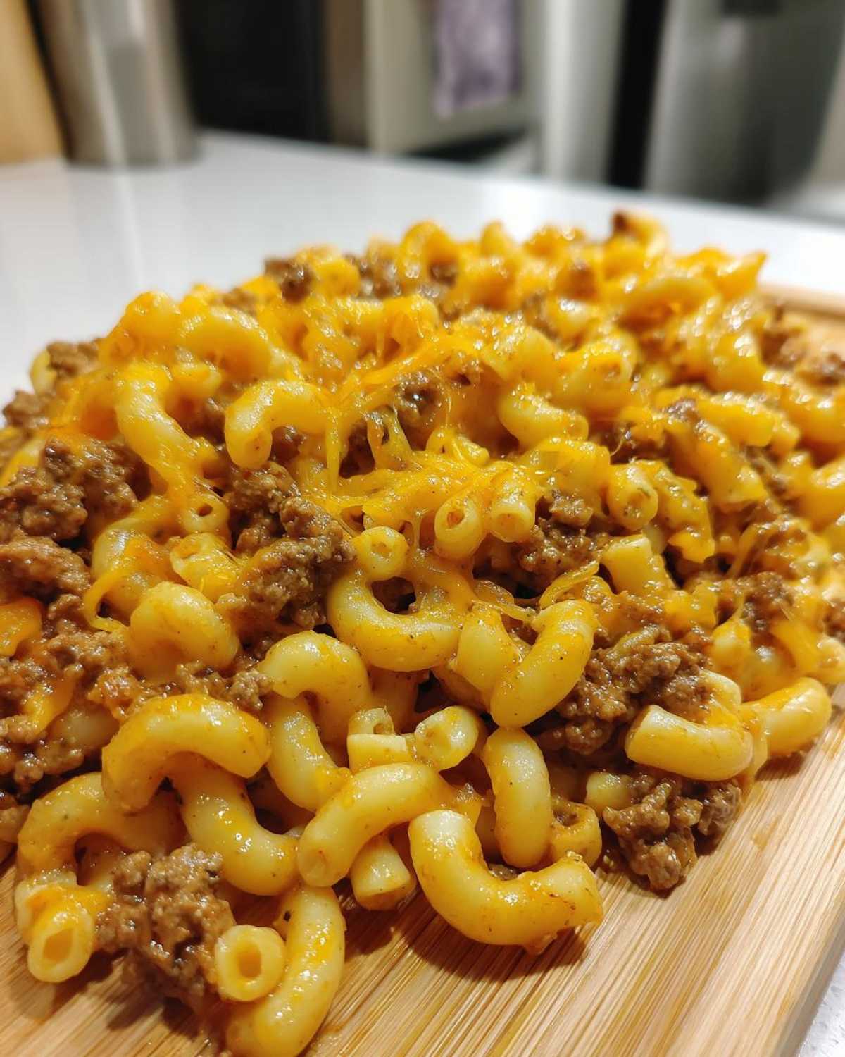 Close-up of creamy macaroni mixed with ground beef and topped with melted cheddar cheese in a cheeseburger pasta skillet.
