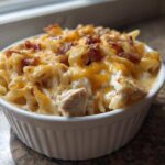 A close-up of a single serving of creamy Chicken Bacon Ranch Casserole topped with melted cheddar and crispy bacon.