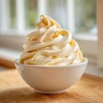 A perfect swirl of creamy, pale yellow banana ice cream served in a small white bowl.